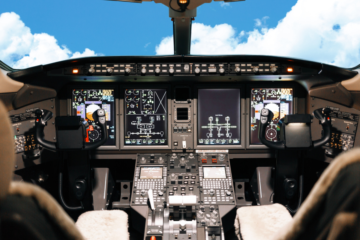 Aircraft cockpit with advanced avionics and controls, set against a bright blue sky with clouds.