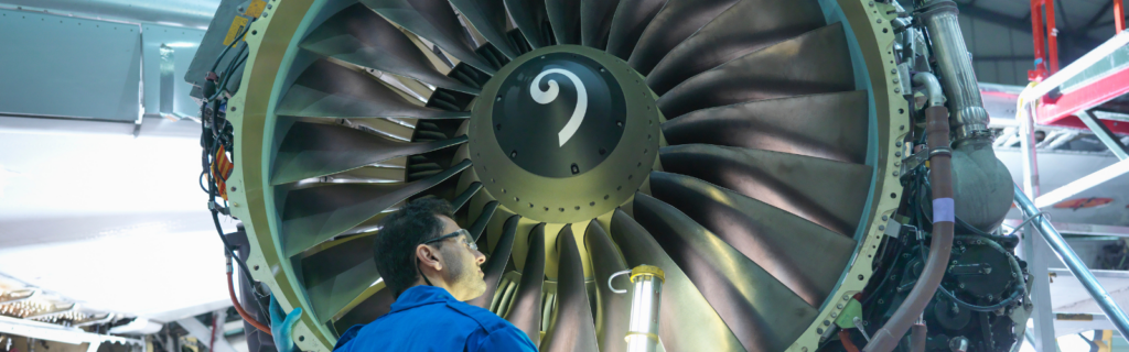 Technician inspecting large aircraft engine during transport process.