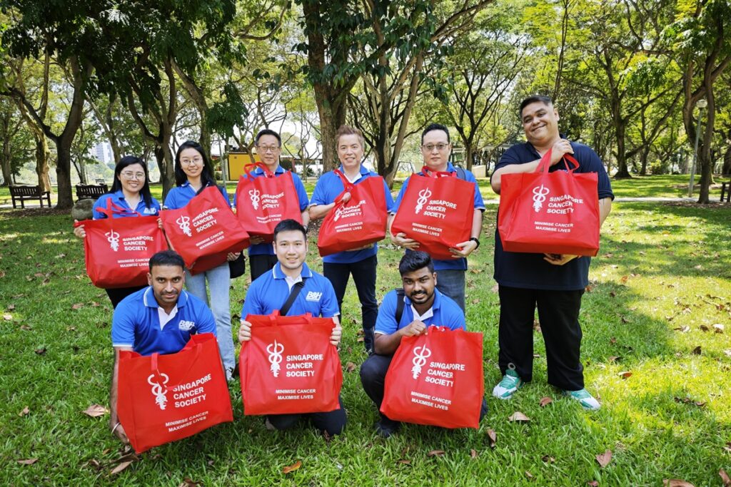 Volunteers holding red bags for Singapore Cancer Society, supporting cancer awareness and charity drives.