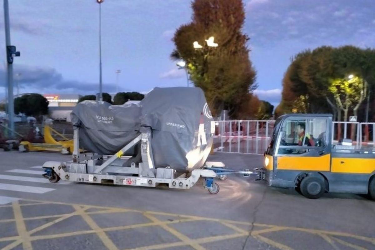 Aircraft engine transport on tarmac with ground support equipment.